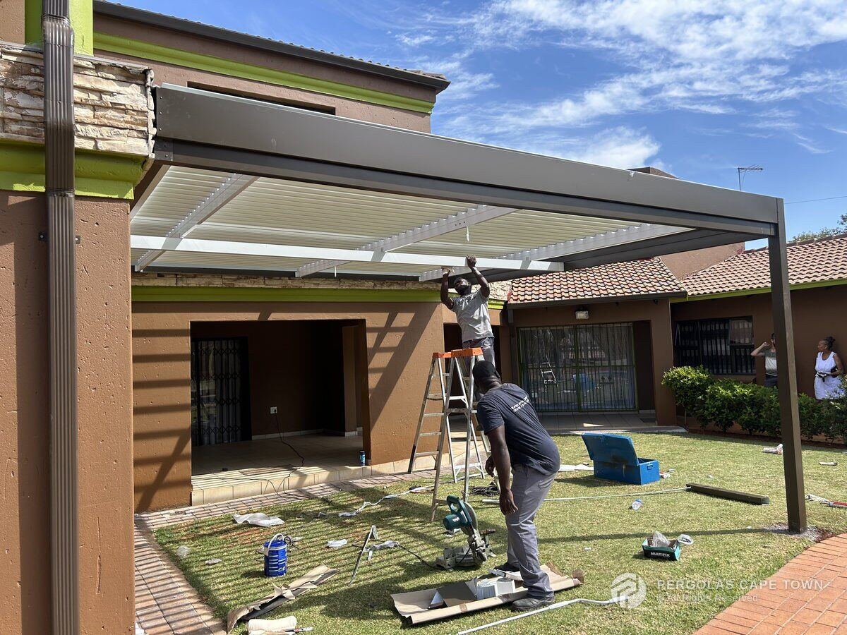 Aluminium Awnings team fitting the white louvre blades into the bronze frame in Hermanus.